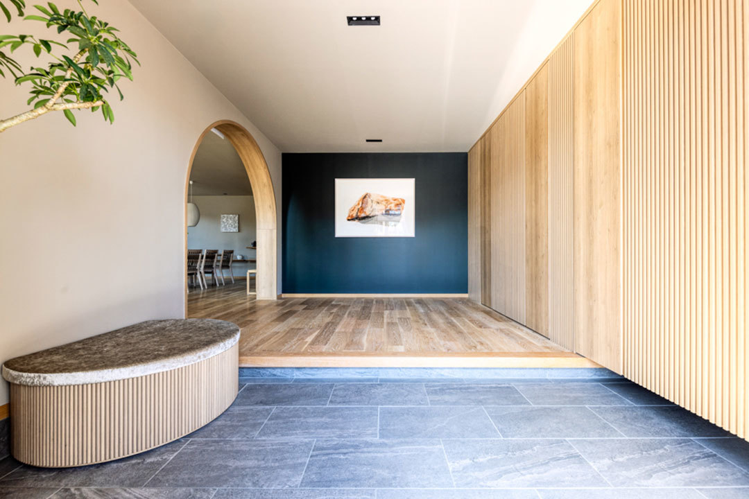 新所沢デシオ展示場_塗装壁をバックに飾られた作家ものの絵画作品がアートを楽しむ家族像を演出